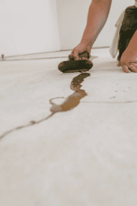 closeup shot of a man filling the floor crack